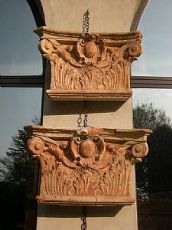 Pendant di capitelli in cotto, con foglie d'acanto e stemma centrale gentilizio